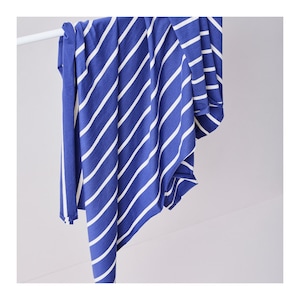 Könnte beinhalten: Ein blauer und weißer gestreifter Stoff mit diagonalen Streifen. Der Stoff ist über eine weiße Stange gelegt.