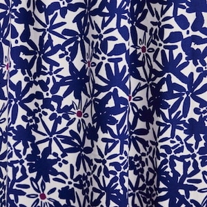 Könnte beinhalten: Weißer Stoff mit einem blauen und rosafarbenen Blumenmuster. Die Blumen sind stilisiert und abstrakt.