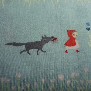 Könnte beinhalten: Ein blauer Stoff mit einem Wolf und einem Mädchen in einem roten Kapuzenkleid, die durch ein Feld mit Blumen gehen. Der Wolf trägt einen Korb.