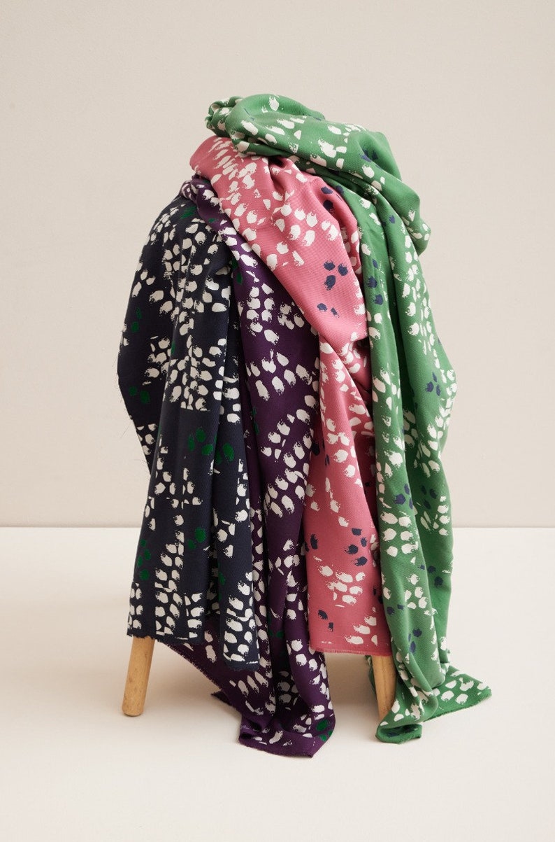 Pu&ograve; includere: Quattro campioni di tessuto con un motivo astratto di pennellate bianche su uno sfondo verde, rosa, viola e blu navy.