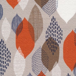Puede incluir: Primer plano de una tela con un patrón repetido de formas de hojas estilizadas. Las hojas son en tonos naranja, marrón, azul marino y blanco, sobre un fondo beige neutro. El diseño tiene una estética moderna de mediados de siglo.