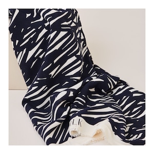 May include: Black and white abstract print fabric with a textured surface. The fabric is folded and the edge is visible.