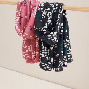 Pu&ograve; includere: Due sciarpe con un motivo astratto bianco e nero. Una sciarpa &egrave; rosa e l'altra &egrave; blu scuro.