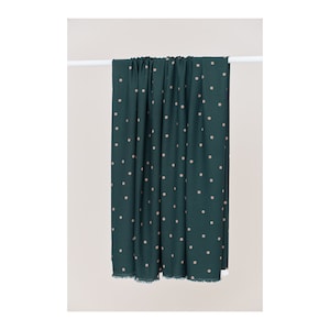 May include: A dark green fabric with a white polka dot pattern. The fabric is hanging from a white rod.