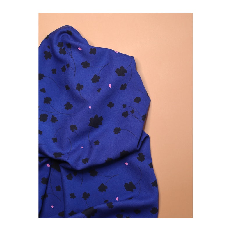 May include: A blue fabric with a black and pink floral pattern. The fabric is folded and has a soft, smooth texture.
