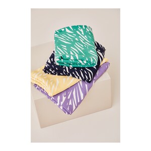 May include: Four fabric swatches with a white abstract pattern on a green, navy blue, yellow, and purple background. The swatches are stacked on top of each other.