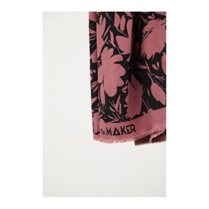 Puede incluir: Una tela rosa con estampado floral negro. La tela tiene un borde deshilachado y el texto "the MAKER" impreso en la parte inferior.