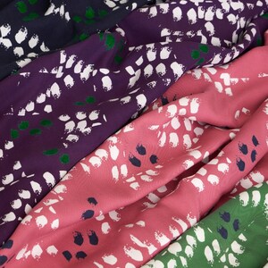 Pu&ograve; includere: Quattro campioni di tessuto con un motivo astratto bianco su sfondo blu scuro, viola, rosa e verde.