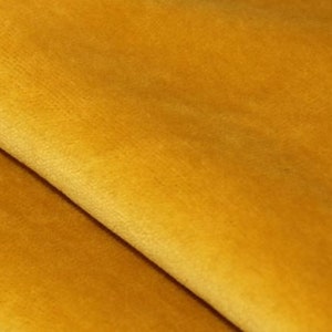 May include: Close-up of a soft, yellow velvet fabric. The fabric has a smooth, luxurious texture.