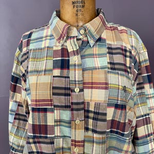 May include: A long-sleeve button-down shirt featuring a patchwork design composed of various plaid fabric squares in shades of blue, tan, red, and white. The shirt includes a pointed collar, a front button placket, and an embroidered RL logo.