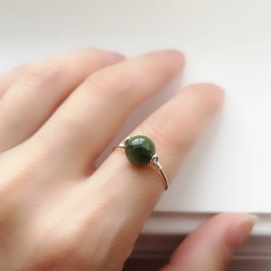 May include: A silver wire ring with a single round green gemstone.