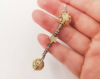 May include: A gold bracelet with two round gold beads and a gold star charm. The bracelet is made of silver wire and has small beads of different colors.