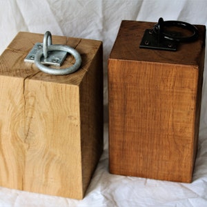 May include: Two wooden doorstops with metal rings. One doorstop is natural wood and the other is stained a dark brown.