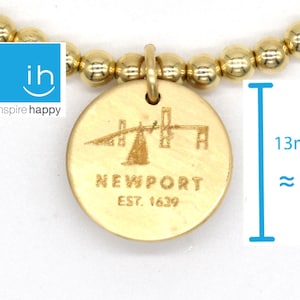 Puede incluir: Pulsera de oro con un dije redondo que presenta un puente y el texto "NEWPORT EST. 1639". El dije tiene un diámetro de aproximadamente 13 mm.