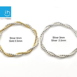 May include: Two beaded bracelets. One is silver and gold, with the text "Silver 3mm Gold 2.5mm". The other is silver, with the text "Silver 3mm Silver 2.5mm". The bracelets are on a white background.