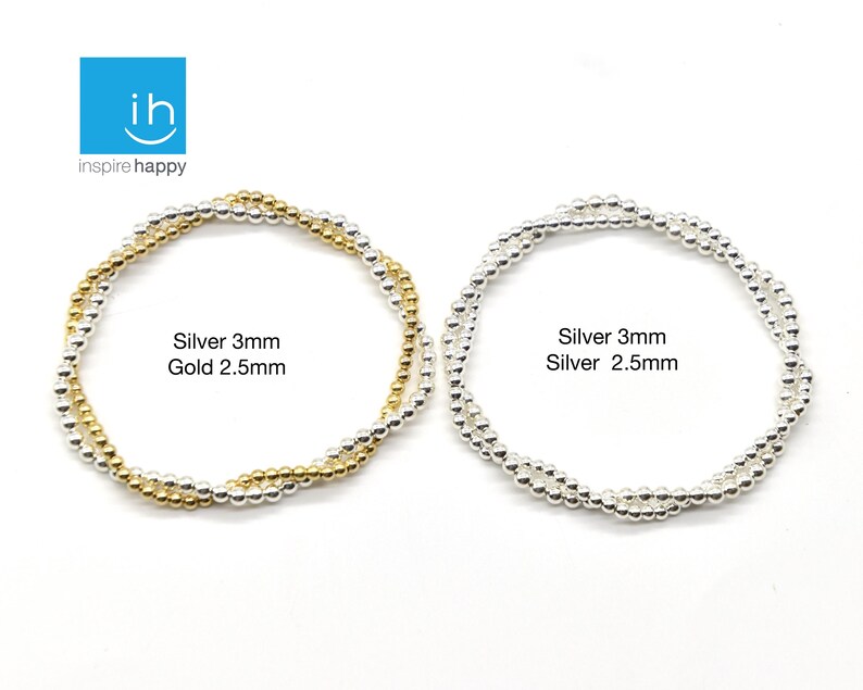 May include: Two beaded bracelets. One is silver and gold, with the text "Silver 3mm Gold 2.5mm". The other is silver, with the text "Silver 3mm Silver 2.5mm". The bracelets are on a white background.