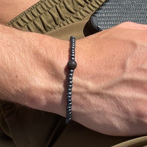 May include: A black beaded bracelet with a single larger black bead in the center.