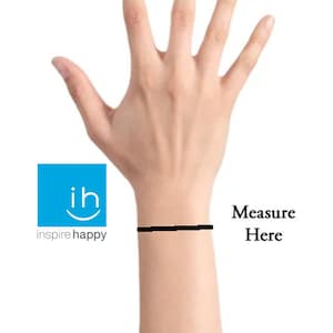 May include: A close-up of a person's wrist with a black line drawn across it. The text "Measure Here" is written next to the line.