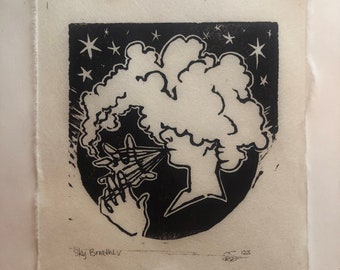 May include: Black and white linocut print of a person with a cloud-like hairstyle, reaching up towards a starry sky. The print is titled "Sky Breath" and signed with the number 123.
