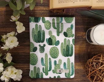 May include: A white zippered pouch with a green cactus print. The pouch has a small brown label with the text "Home With Print Co."
