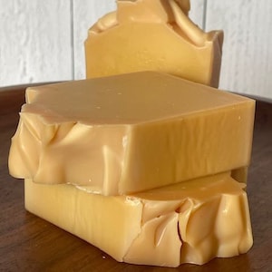 May include: Three bars of handmade soap stacked on top of each other. The soap is a light yellow colour and has a slightly textured surface.
