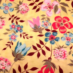 Puede incluir: Una tela amarilla con un patrón floral. Las flores son en tonos de rosa, rojo, azul y verde. La tela tiene un aspecto vintage.