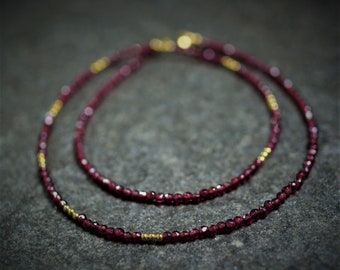 Delicate chain of dark red faceted garnet and golden intermediate parts, garnet muck