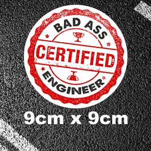 Könnte beinhalten: Ein runder Aufkleber in Rot und Weiß mit dem Text "Bad Ass Certified Engineer" in Schwarz. Der Aufkleber ist 9 cm x 9 cm groß und befindet sich auf einem schwarzen Asphalt-Hintergrund.