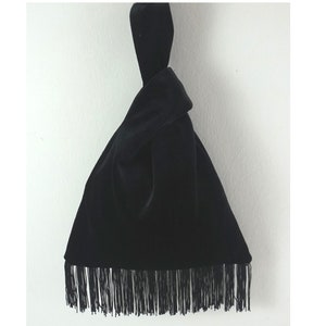 Könnte beinhalten: Eine schwarze Samt-Tasche mit einem geknoteten Oberteil und einem Fransenbesatz.