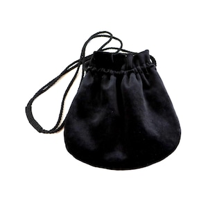 Puede incluir: Una bolsa de terciopelo negro con cordón a juego. La bolsa tiene una base redondeada y una parte superior fruncida. El cordón es grueso y parece estar hecho de tela trenzada.