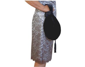 Zwarte ovale handtas met knoop en kwastje.