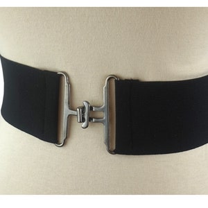 Peut inclure: Une ceinture élastique noire avec une boucle argentée. La boucle est de forme rectangulaire simple avec un fermoir central unique.