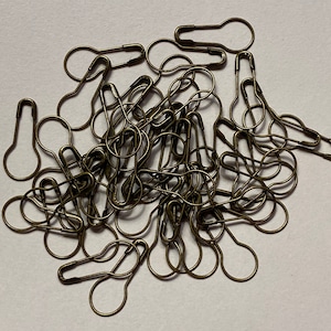 May include: A pile of antique gold safety pins with a rounded head. The safety pins are all closed and tangled together.