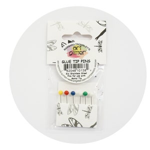 May include: A package of six stainless steel glue tip pins with colorful heads. The package includes yellow, red, blue, and green pins. The packaging features the text "GLUE TIP PINS" and "art glitter".