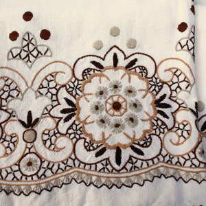Könnte beinhalten: Weißer Stoff mit brauner und beigefarbener Stickerei eines Blumendesigns. Die Stickerei weist komplizierte Details und ein zartes Muster auf.