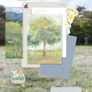 Op de afbeelding: Een briefpapier set bestaande uit een brief met een hert-logo, een bladwijzer met een landschap en konijnen, een ansichtkaart met een boom, een blauwe envelop en twee stickers met gele bloemen en twee konijnen in een mandje.