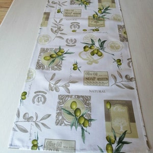 Pode incluir: Caminho de mesa branco com um padrão repetido de ramos de oliveira, azeitonas e etiquetas que dizem "Olive Oil Soap Natural".