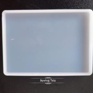 May include: A rectangular, clear silicone mold with a white border. The mold is empty and ready for use. The text "Sewing Tale" is printed in white at the bottom of the image.