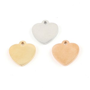 May include: Three heart-shaped metal charms in silver, gold, and rose gold. Each charm has a small loop at the top for attaching to a necklace or bracelet.