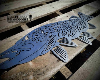 May include: A metal cutout of a fish with a detailed design. The fish is painted a dark blue color and is sitting on a wooden pallet. The text "BULLETPROOF TECHNOLOGIES" is visible in the top left corner of the image.