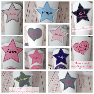 Könnte beinhalten: Eine Sammlung von 10 personalisierten Stern- und Herzförmigen Stoff-Patches in verschiedenen Farben, darunter Pink, Blau, Grau und Weiß. Die Patches zeigen Namen wie "Maria", "Maja", "Ida", "Anni", "Tilda", "Tamina", "Medine Sura", "Sofia" und "Giuliano". Der Text "Pink auf Dunkelblau" und "Beere auf kräftigem Rosa" ist ebenfalls auf den Patches zu sehen.