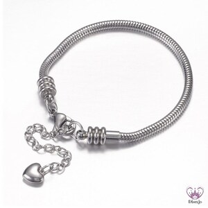 May include: A silver snake chain bracelet with a heart charm and a lobster clasp.