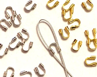 May include: A close-up of silver and gold crimp beads, used for jewelry making. The beads are in the shape of a loop with a crimping end. There are two pieces of silver wire in the image.