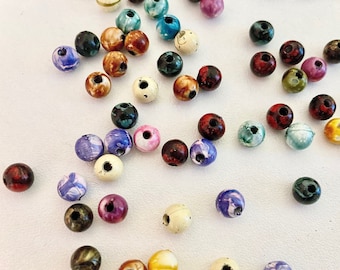 Puede incluir: Una colección de cuentas redondas de colores con varios patrones y diseños. Las cuentas están hechas de madera y tienen un acabado liso y pulido.