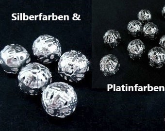 Puede incluir: Cuentas de metal de color plateado y platino con un diseño decorativo. Las cuentas son redondas y tienen una superficie texturizada.