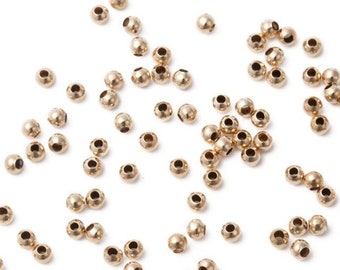 May include: A scattering of small, gold-colored metal beads on a white background.
