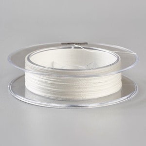 Può includere: Un'bobina di filo bianco avvolta attorno a una bobina di plastica trasparente.