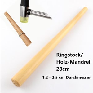 Può includere: Un mandrino per anelli in legno chiaro, lungo circa 28 cm, con un diametro da 1,2 a 2,5 cm. L'immagine mostra anche un misuratore di anelli e un piccolo martello. Il testo sull'immagine recita "Ringstock/Holz-Mandrel 28cm" e "1.2 - 2.5 cm Durchmesser."