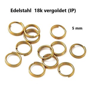 Op de afbeelding: Goudkleurige roestvrijstalen splitringen, 5 mm in diameter, afgebeeld tegen een witte achtergrond. De ringen zijn dubbel lusvormig en hebben een glanzende afwerking. De tekst "Edelstahl 18k vergoldet (IP)" staat bovenaan.