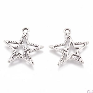 Peut inclure: Deux breloques en forme d'étoile argentées avec une surface texturée. Chaque breloque a une petite étoile découpée au centre.